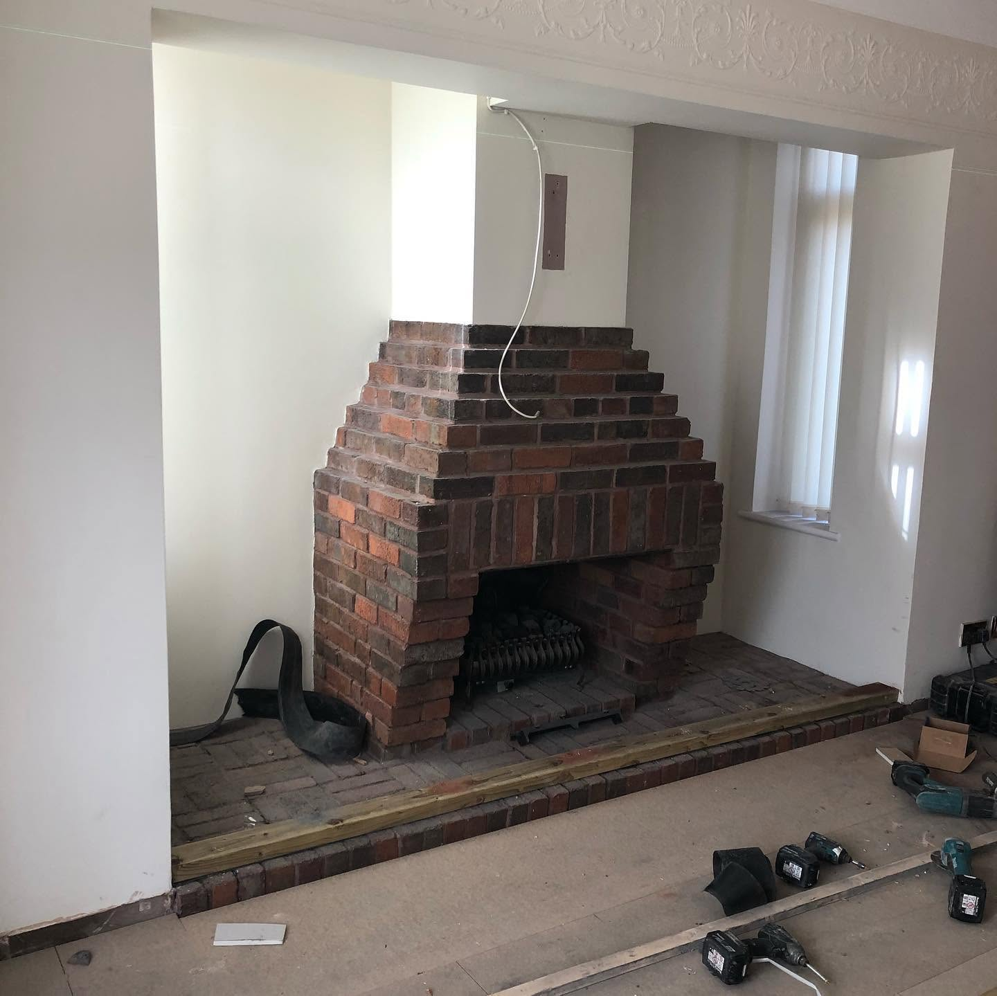 Timber studwork frame built around chimney breast with TV recess opening — mid-build media wall by RG