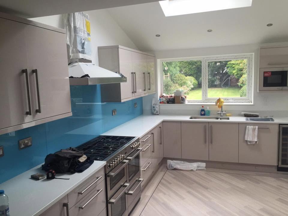 Oak kitchen with blue glass splashback and integrated appliances